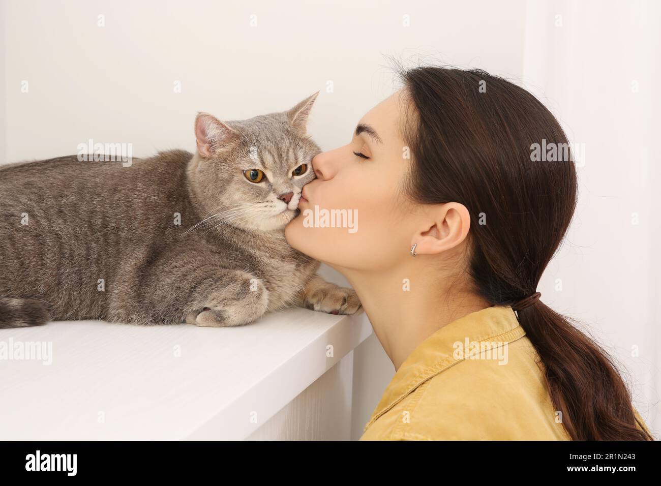 Jeune femme embrassant son adorable chat à la maison Banque D'Images