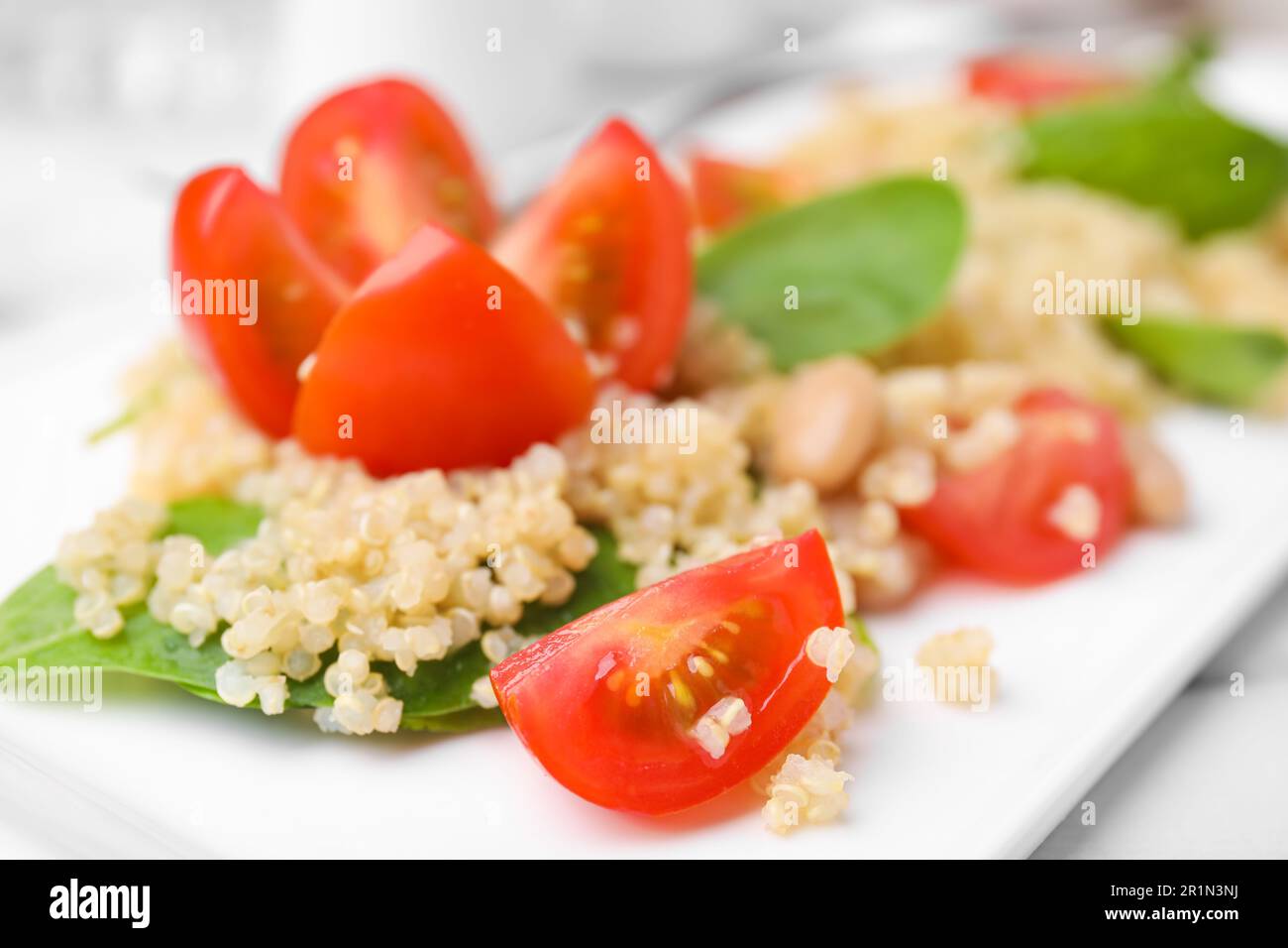 Délicieuse salade de quinoa aux tomates, aux haricots et aux feuilles d'épinards, en gros plan Banque D'Images