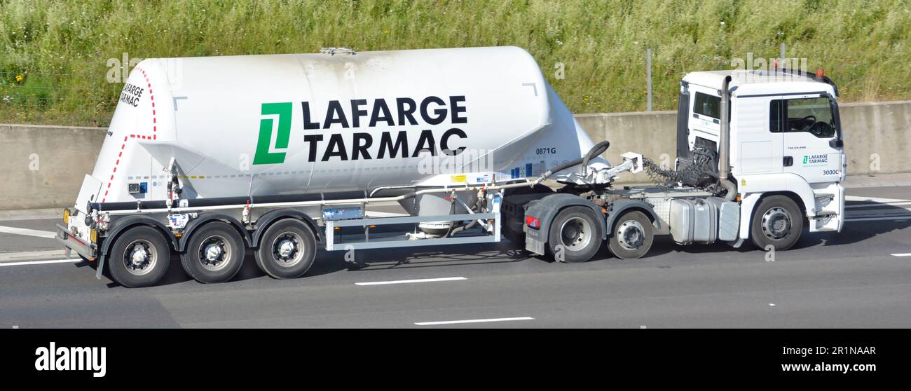 Vue latérale porte-poudre de ciment en vrac LaFarge sur remorque de camion-citerne articulée tractée par camion hgv blanc roulant le long de l'autoroute M25 Essex Angleterre Royaume-Uni Banque D'Images