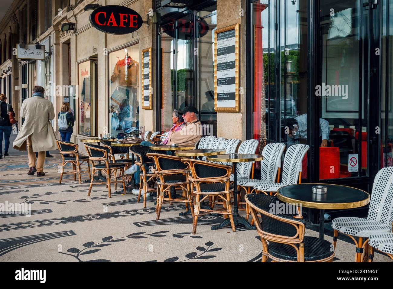 Couple assis dans un café en plein air avec des tables traditionnelles millésimes dans la rue de Paris, France. Banque D'Images Couple assis dans un café en plein air avec des tables traditionnelles millésimes dans la rue de Paris, France. Banque D'Images