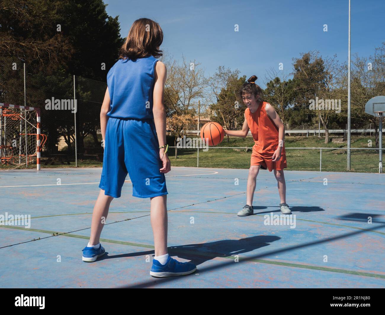 Un à un entre deux jeunes joueurs de basket-ball sur un terrain en plein air par temps ensoleillé. Banque D'Images