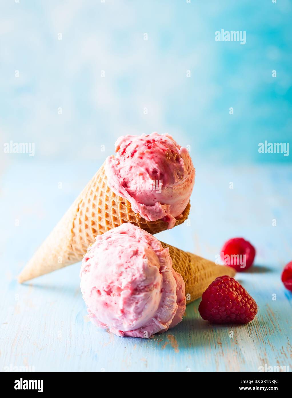 Crème glacée à la framboise en cône de cachets sur fond bleu Banque D'Images