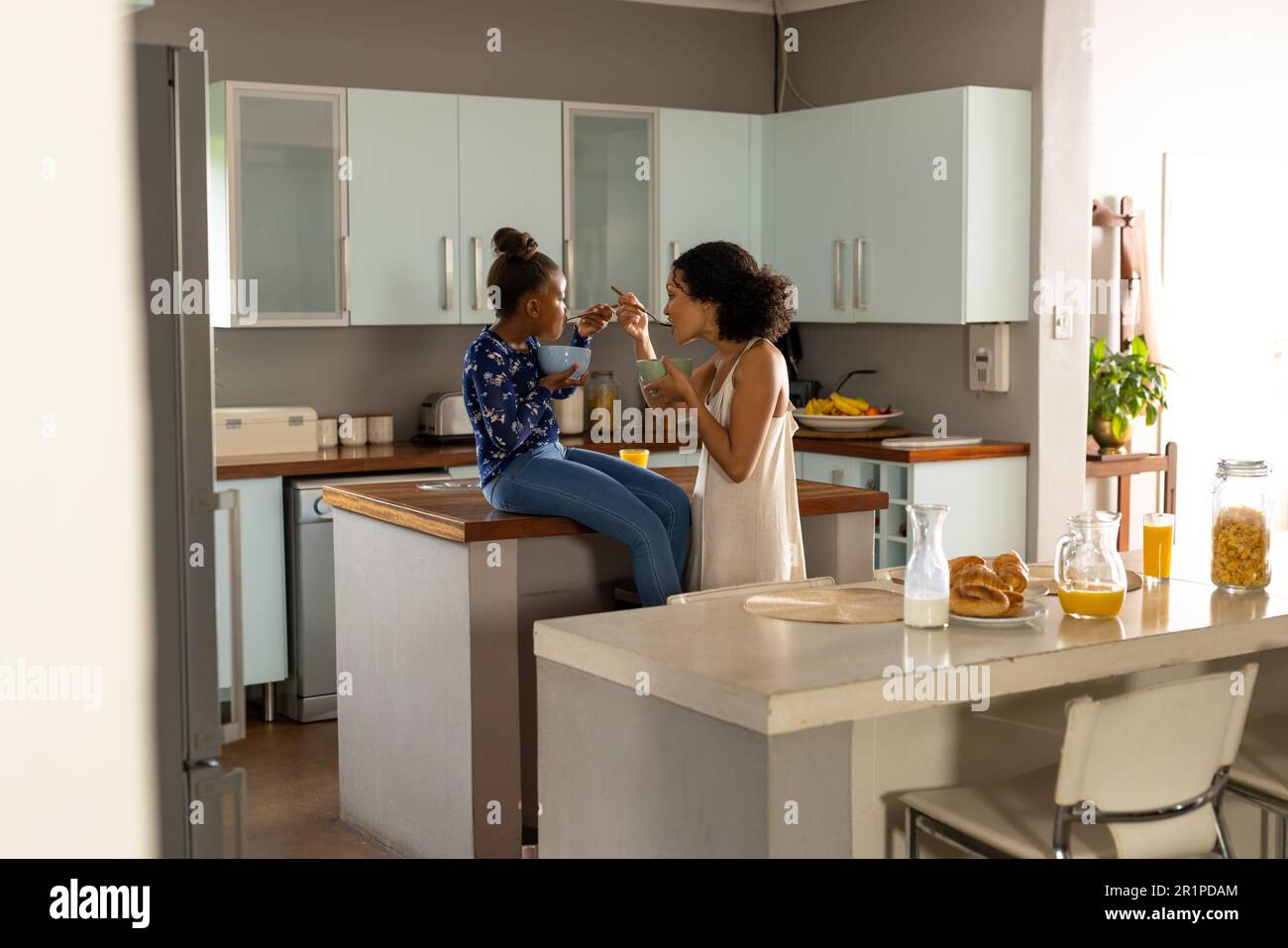 Bonne mère africaine américaine et fille dans la cuisine manger le petit déjeuner ensemble, espace copie Banque D'Images