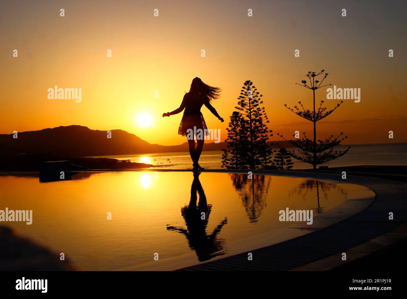 Jeune femme près de la piscine au lever du soleil, Kiotari, Rhodes, Grèce Banque D'Images