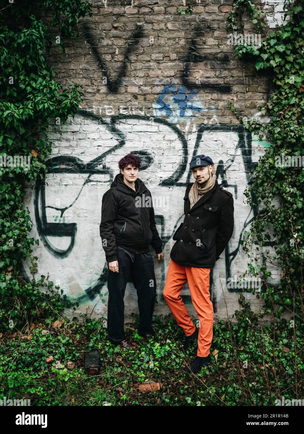 Couple non binaire devant le mur avec graffiti Banque D'Images