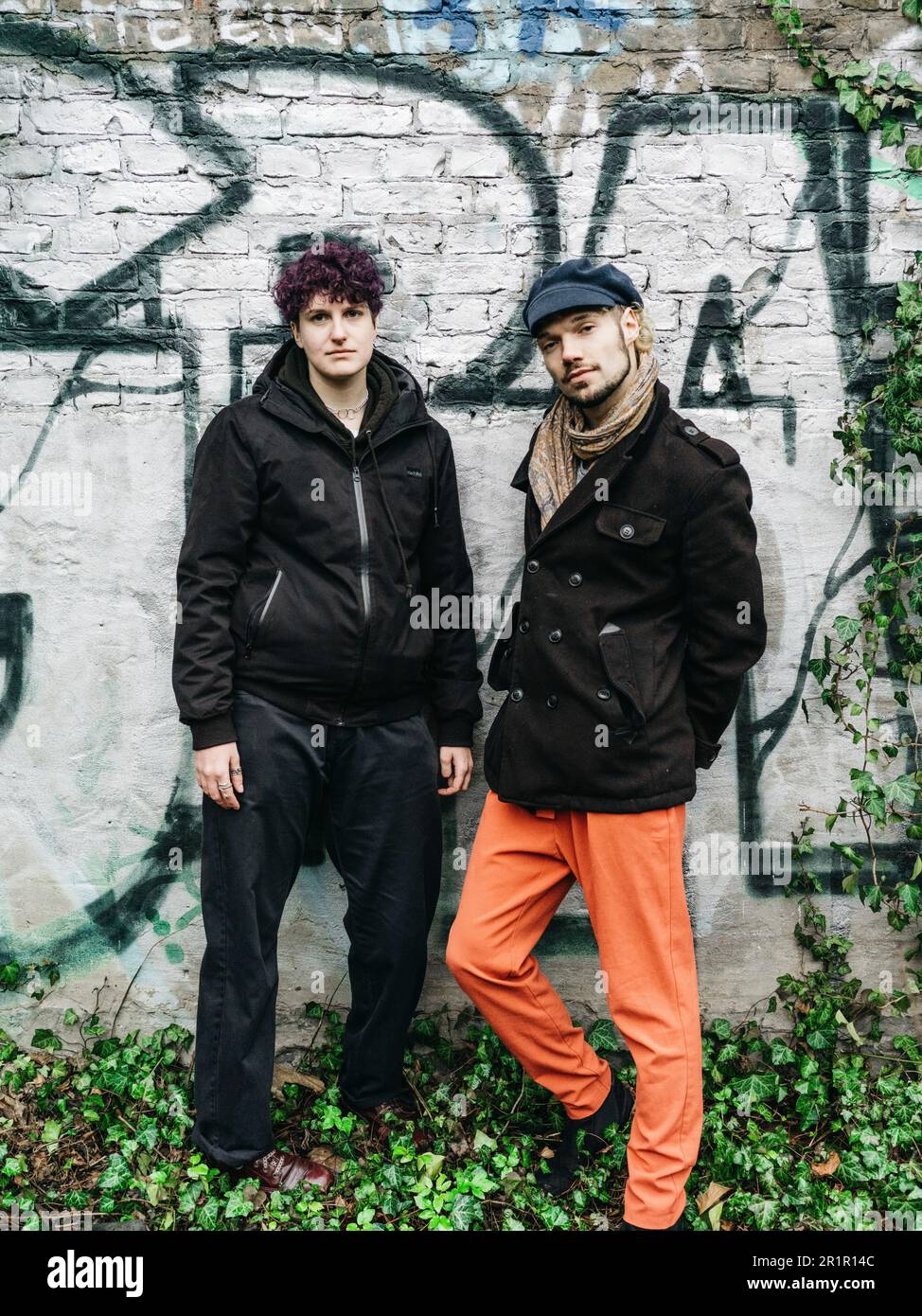 Couple non binaire devant le mur avec graffiti Banque D'Images
