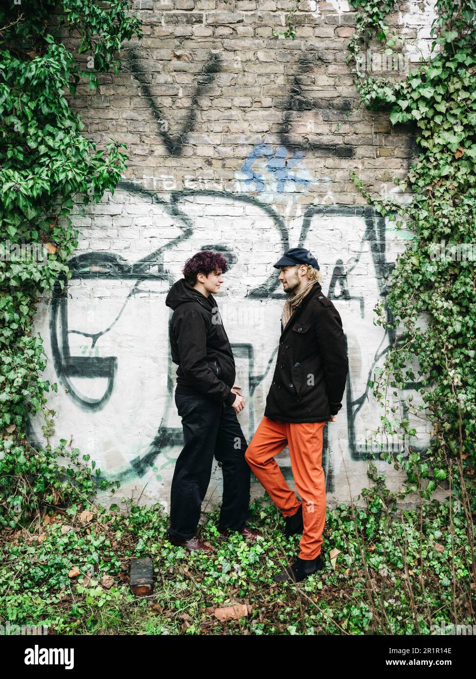 Couple non binaire devant le mur avec graffiti Banque D'Images