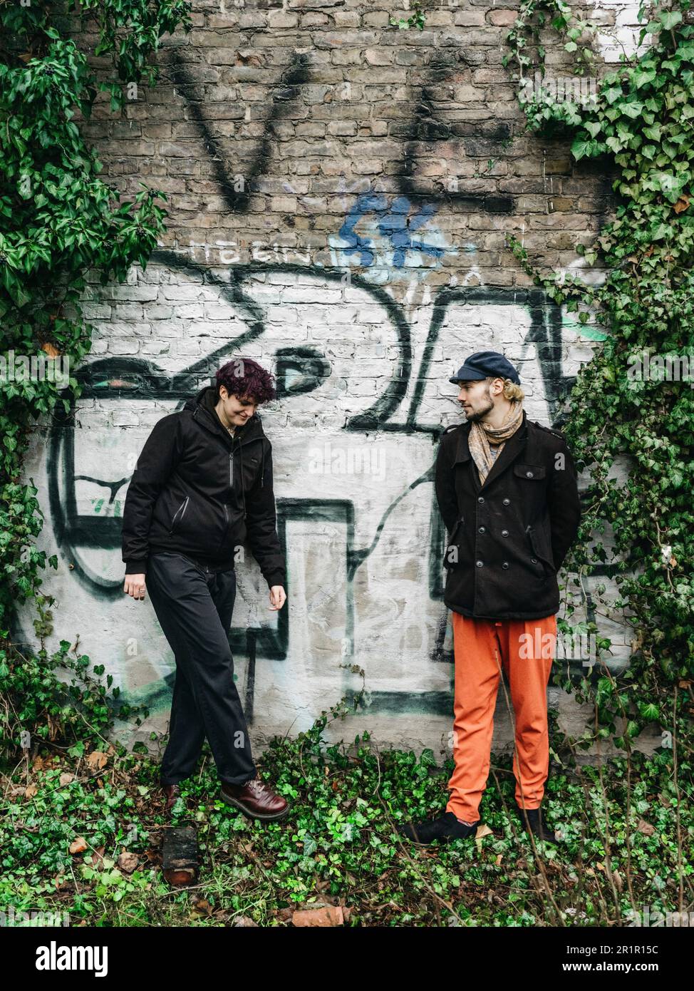 Couple non binaire devant le mur avec graffiti Banque D'Images