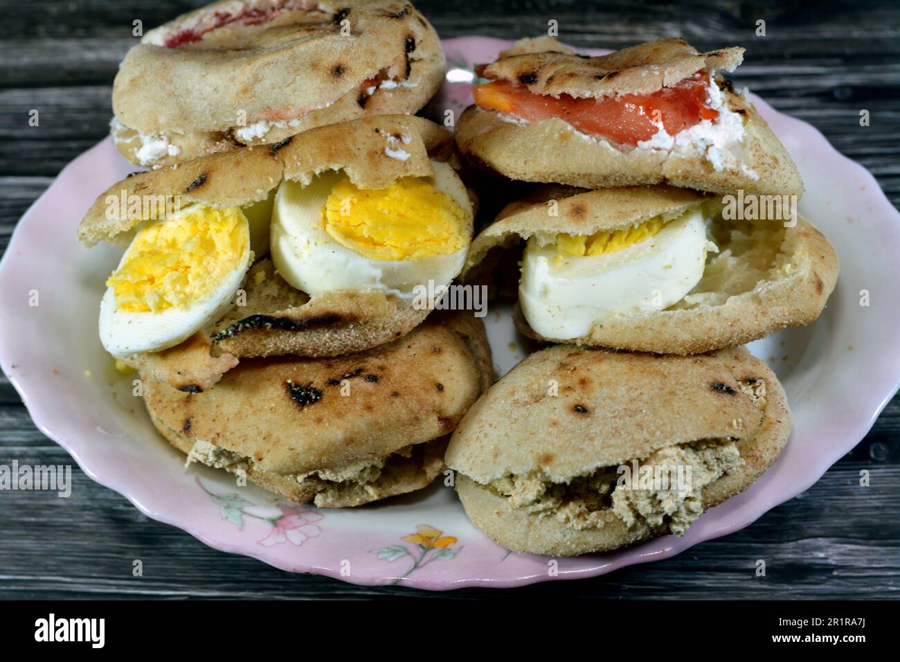 Une assiette de sandwiches au fromage blanc Feta avec des tranches de tomates, de la tahini halva traditionnelle ou Halawa Tahiniya et des tranches d'œufs durs insi Banque D'Images