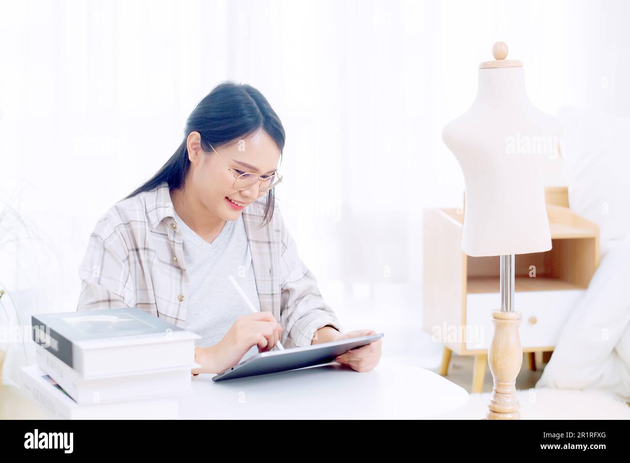Femme souriante de mode assis à une table travaillant sur une tablette numérique Banque D'Images