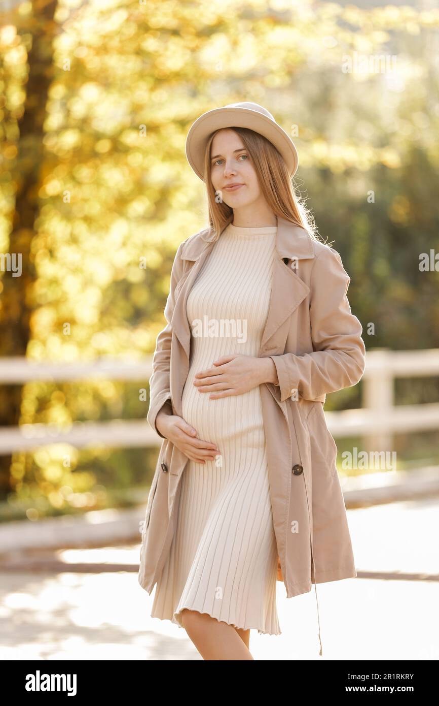 photo de la femme enceinte tient les mains sur le ventre dans le parc  d'automne. Jeune femme en maternité robe chaude et manteau attendant la  naissance de bébé. Grossesse, mothe Photo Stock -