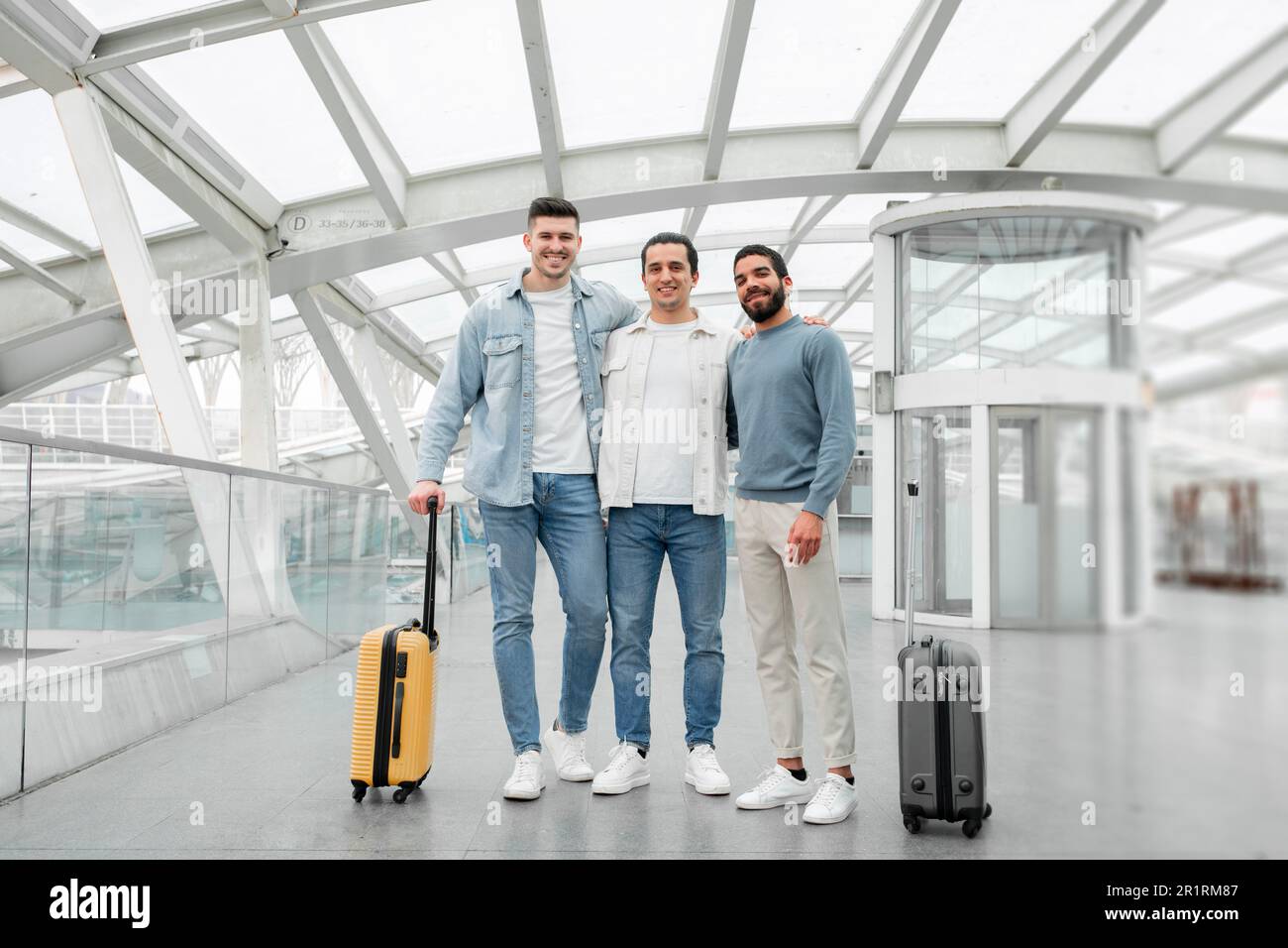 Trois amis hommes avec des valises de voyage qui se posent à l'aéroport Banque D'Images
