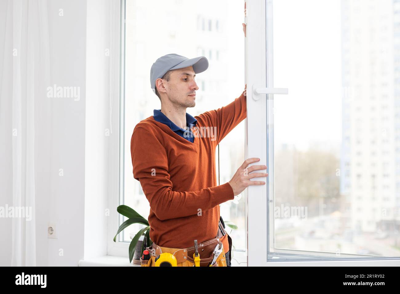 Workman dans des combinaisons d'installer ou d'ajustement des fenêtres en plastique dans la salle de séjour à la maison Banque D'Images