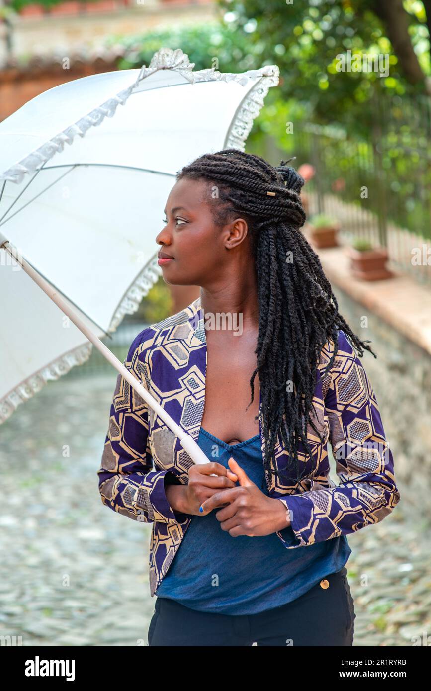 Portrait d'une femme africaine avec un tresses de dreadlocks avec parasol.  Une jeune femme heureuse qui se sent confiante dans son style. Femme à la  mode debout Photo Stock - Alamy
