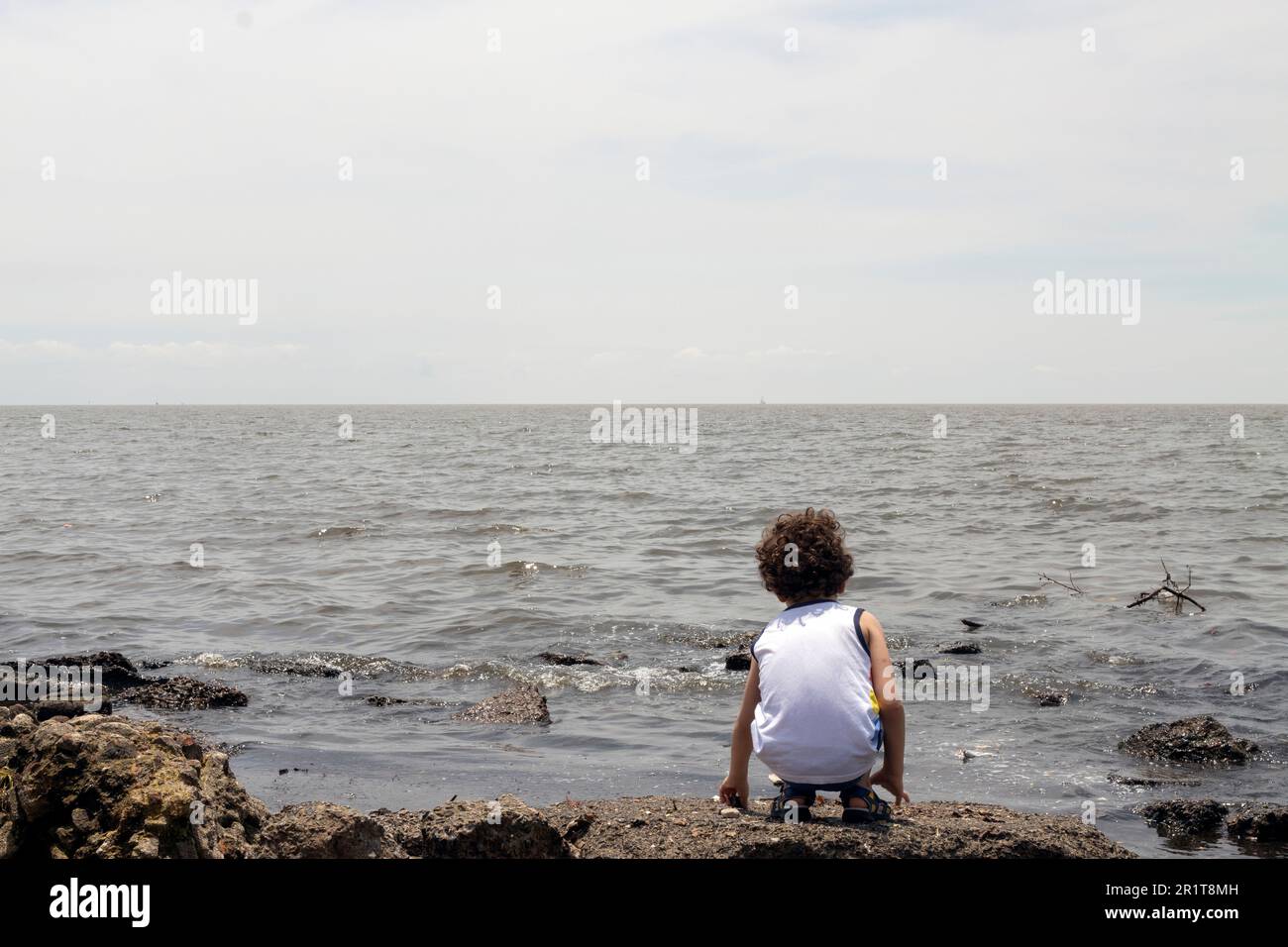 petit garçon regardant la rivière polluée de la rive, concept environnemental Banque D'Images