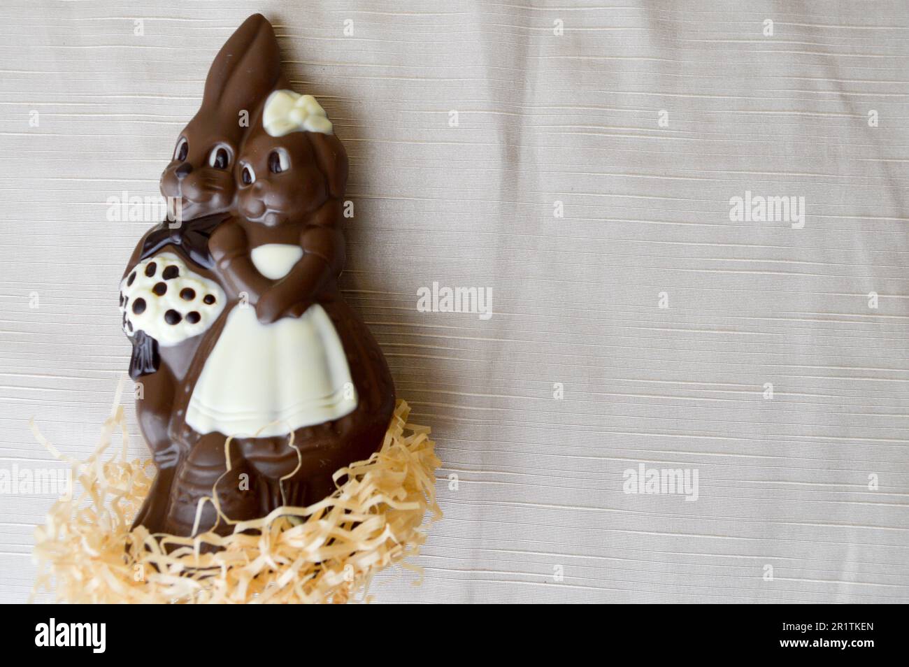 Deux lapins au chocolat. Deux lièvres au chocolat savoureuses et enveloppantes, un couple affectueux sur fond beige clair. Banque D'Images