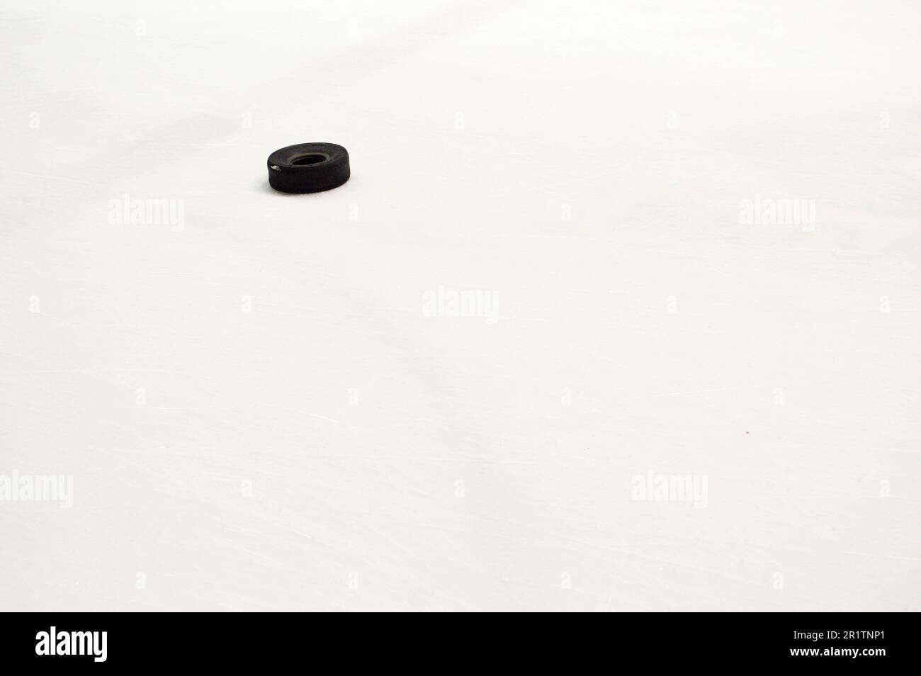 Petit pneu en caoutchouc noir pour l'entraînement d'une partie de hockey sur la glace blanche de l'arène de hockey Banque D'Images