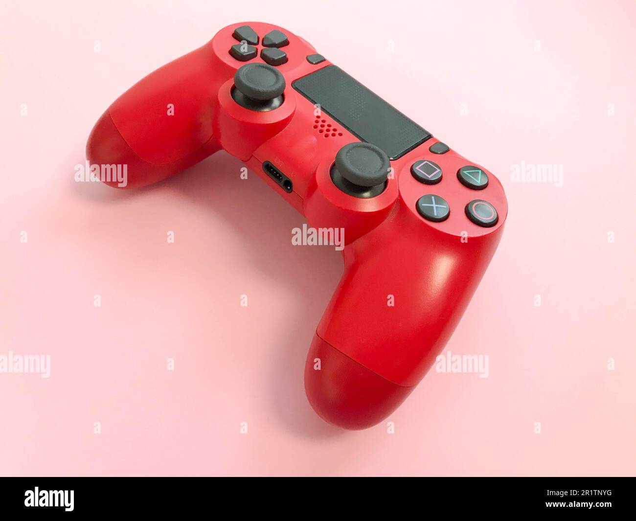 Beau rouge numérique moderne nouveau joystick de jeu pour jeux vidéo d'ordinateur manette de jeu sur un fond rose. Banque D'Images