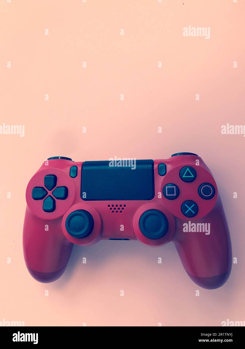 Beau rouge numérique moderne nouveau joystick de jeu pour jeux vidéo d'ordinateur manette de jeu sur un fond rose. Banque D'Images