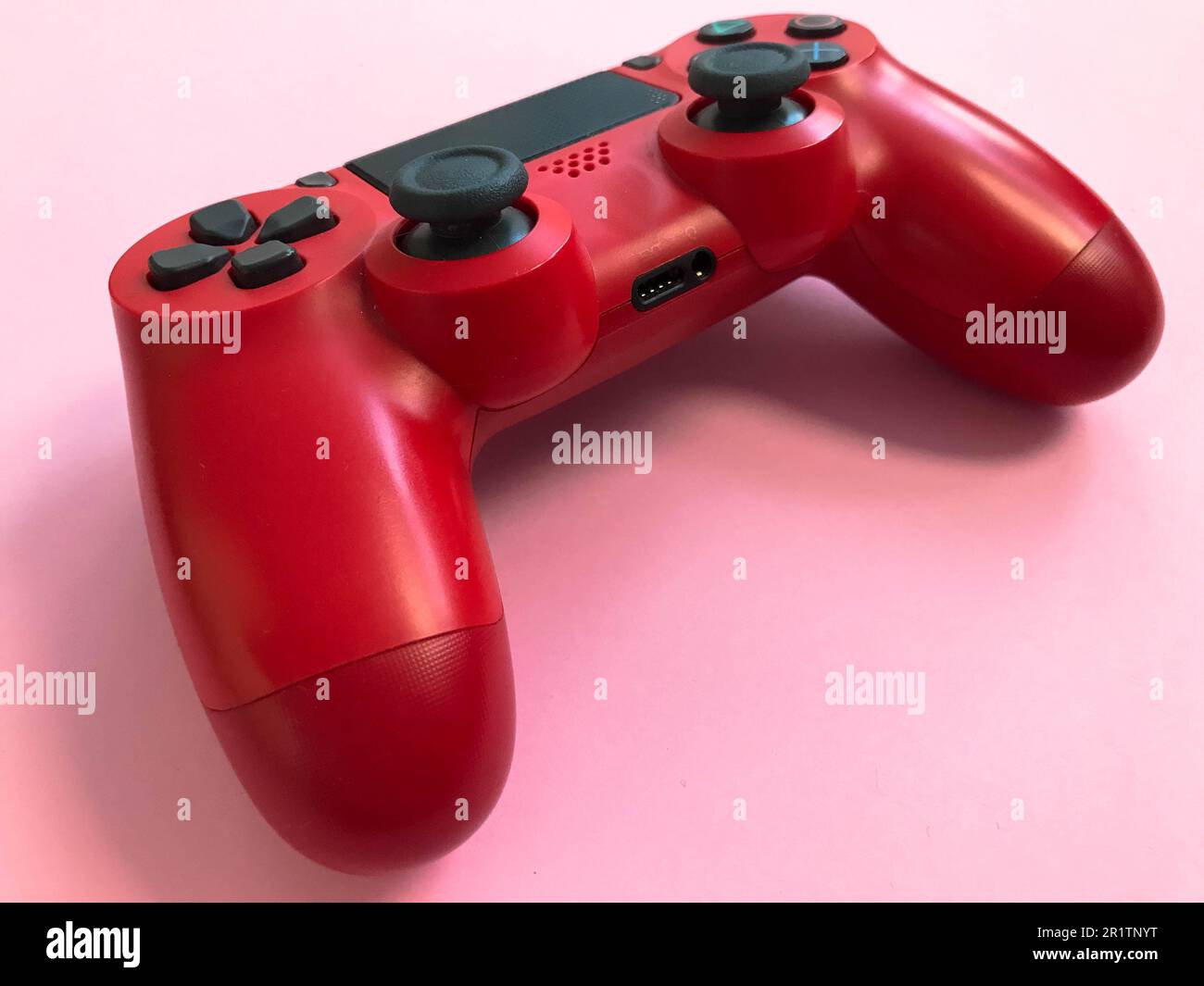 Beau rouge numérique moderne nouveau joystick de jeu pour jeux vidéo d'ordinateur manette de jeu sur un fond rose. Banque D'Images