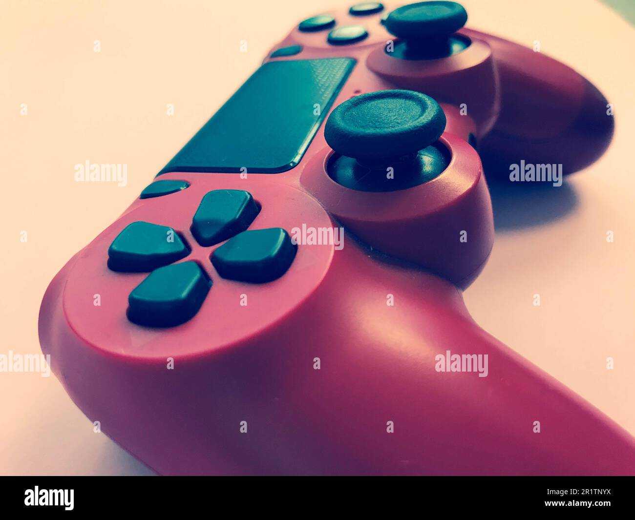 Beau rouge numérique moderne nouveau joystick de jeu pour jeux vidéo d'ordinateur manette de jeu sur un fond rose. Banque D'Images
