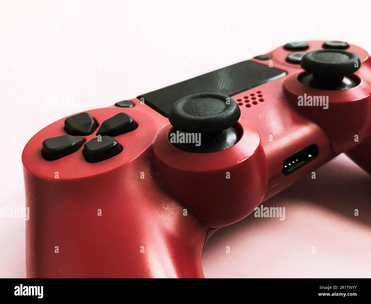 Beau rouge numérique moderne nouveau joystick de jeu pour jeux vidéo d'ordinateur manette de jeu sur un fond rose. Banque D'Images