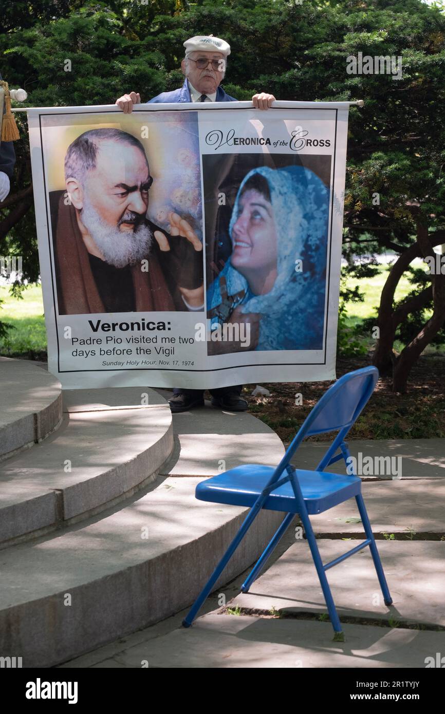 Lors d'une cérémonie couronnante en mai et derrière la chaise utilisée par Veronica Lueken, une catholique dévorée tient sa photo et l'une des Padre Pio. À Queens, New York. Banque D'Images