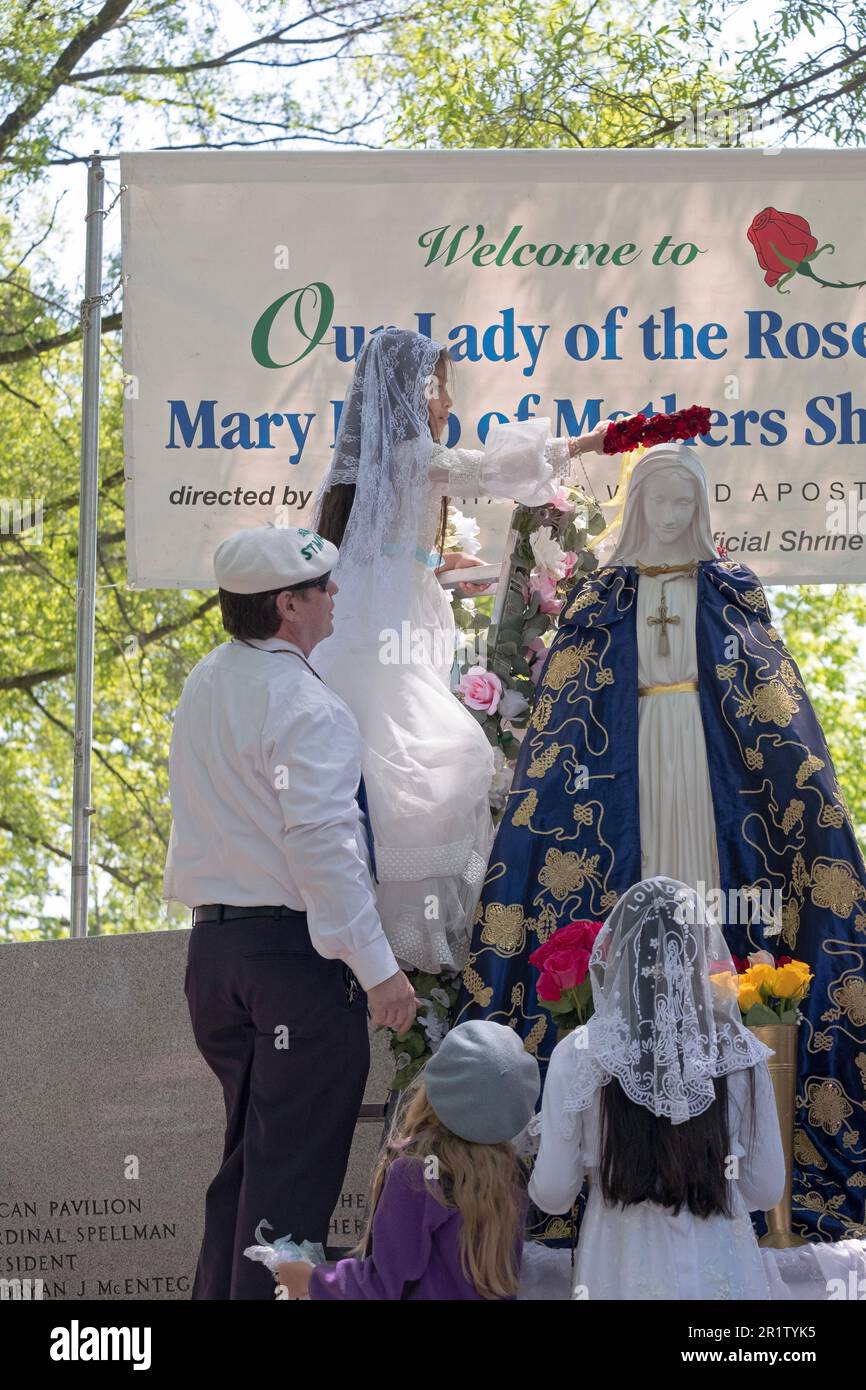 Une fille hispanique de 8 ans de Corona se produit lors de la cérémonie catholique romaine de mai. Avant de couronnement, elle met des fleurs sur la statue de Marie. Banque D'Images