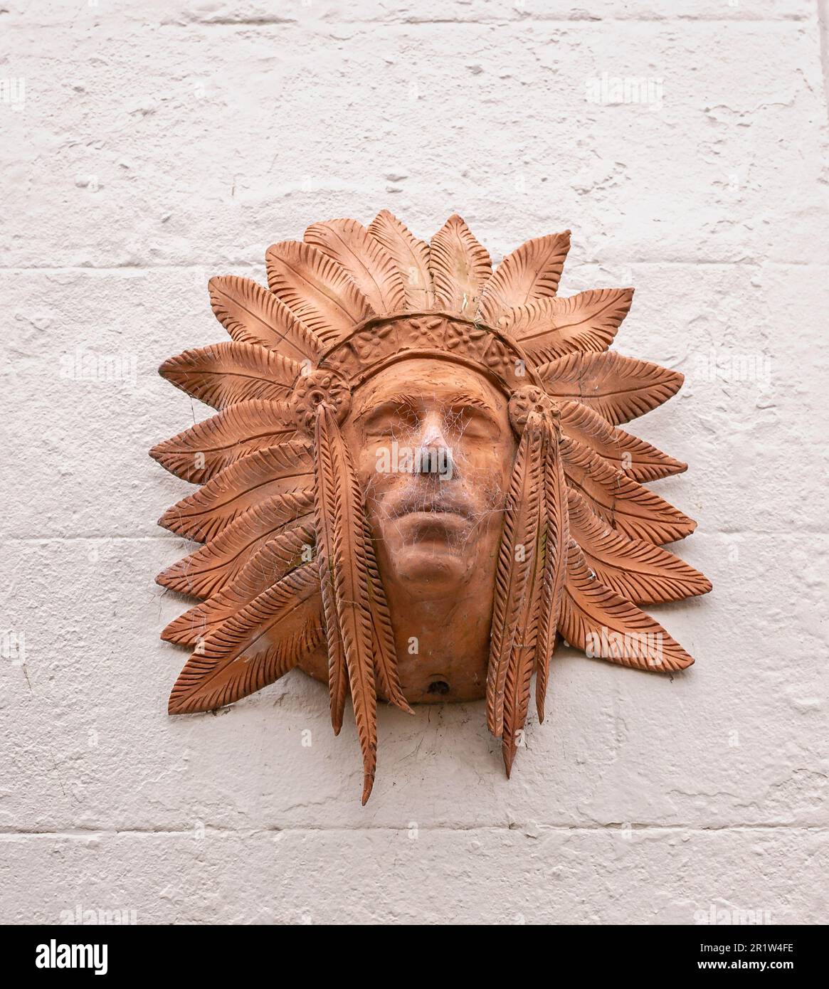 Gros plan de la sculpture en argile de la tête indienne rouge avec une coiffe en plumes sur le mur à Whitby, dans le Yorkshire, au Royaume-Uni, le 22 mai 2018 Banque D'Images