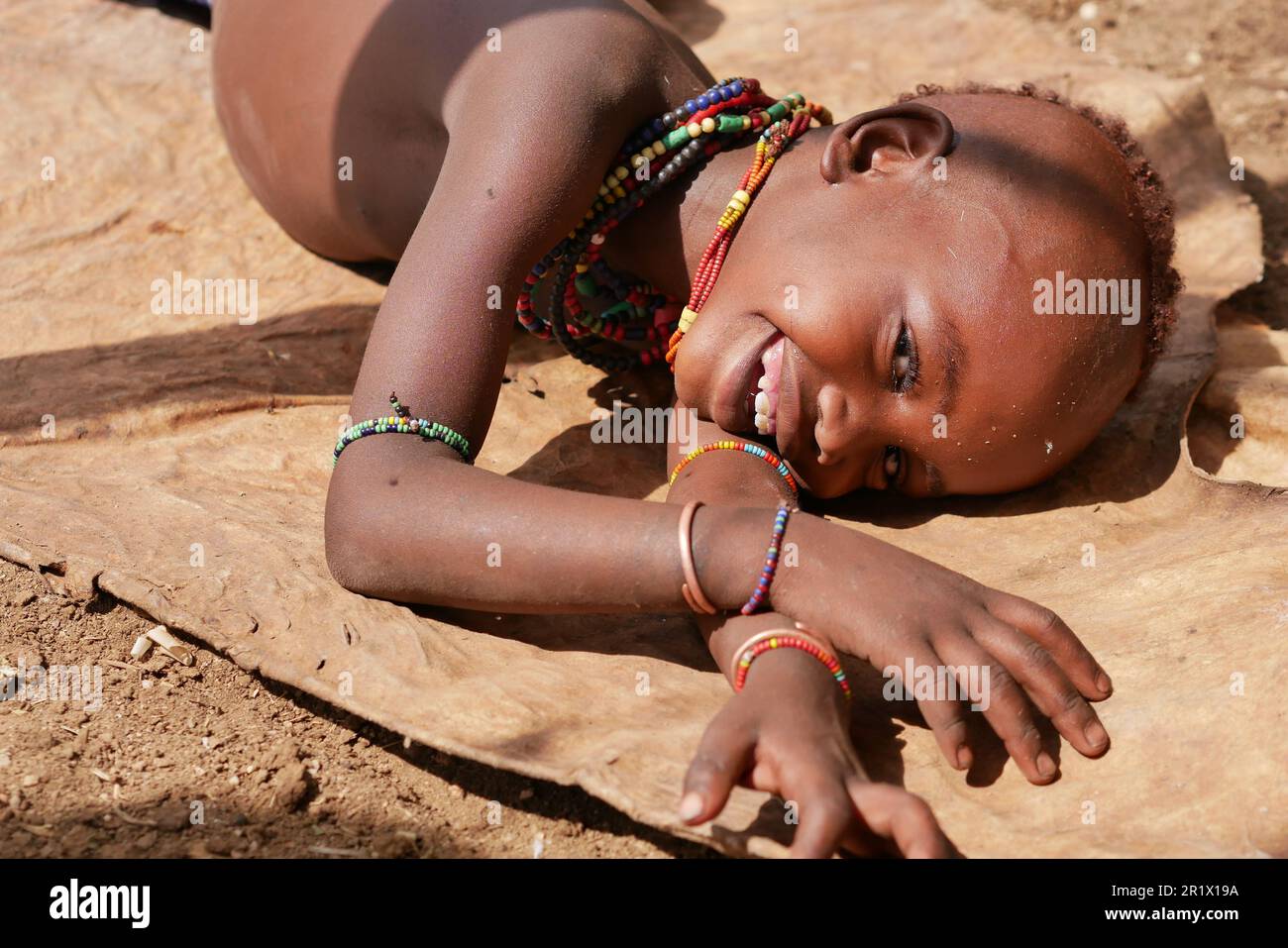Omo Valley, Éthiopie – 11.19.2022 : enfant de la tribu hamar allongé sur le sol et en riant Banque D'Images