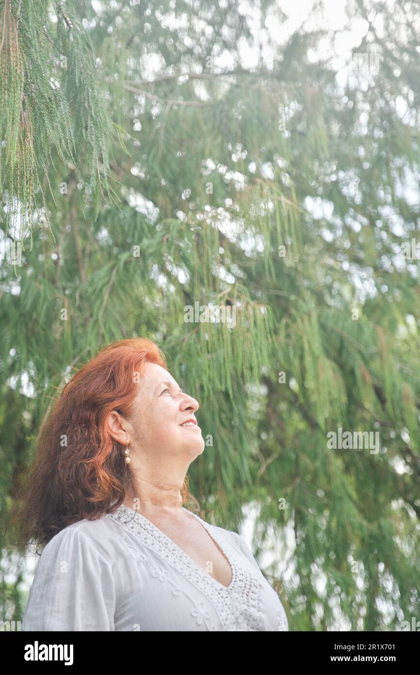 Portrait d'une femme latino-américaine aux cheveux rouges souriant, rêvant de rêver dans la nature. Composition lumineuse avec espace de copie. Concept: La paix de l'esprit et h Banque D'Images