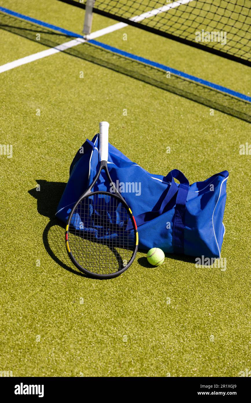 Raquette de tennis, ballon et sac de sport sur le sol par filet sur terrain de pelouse plein air ensoleillé, espace de copie Banque D'Images