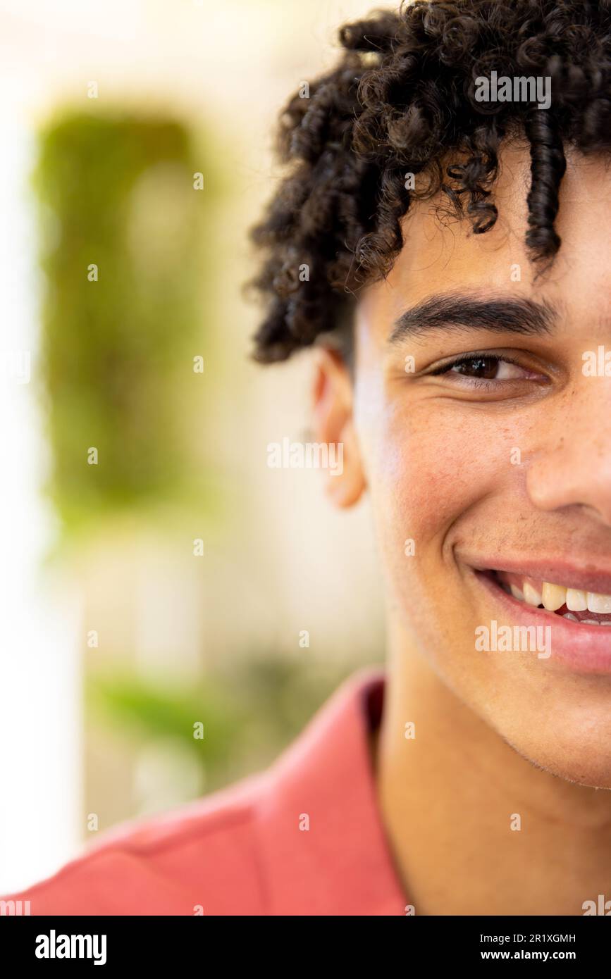 Demi portrait d'un homme biracial heureux avec des cheveux noirs bouclés souriant à la maison, avec espace de copie Banque D'Images