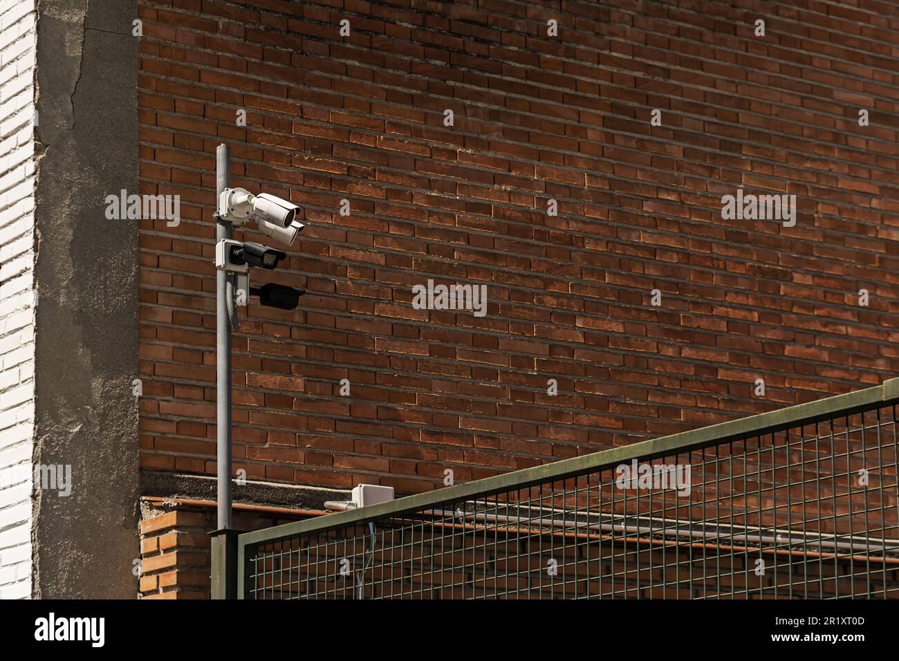 Un poste avec des caméras de surveillance à côté d'un mur en brique d'argile Banque D'Images