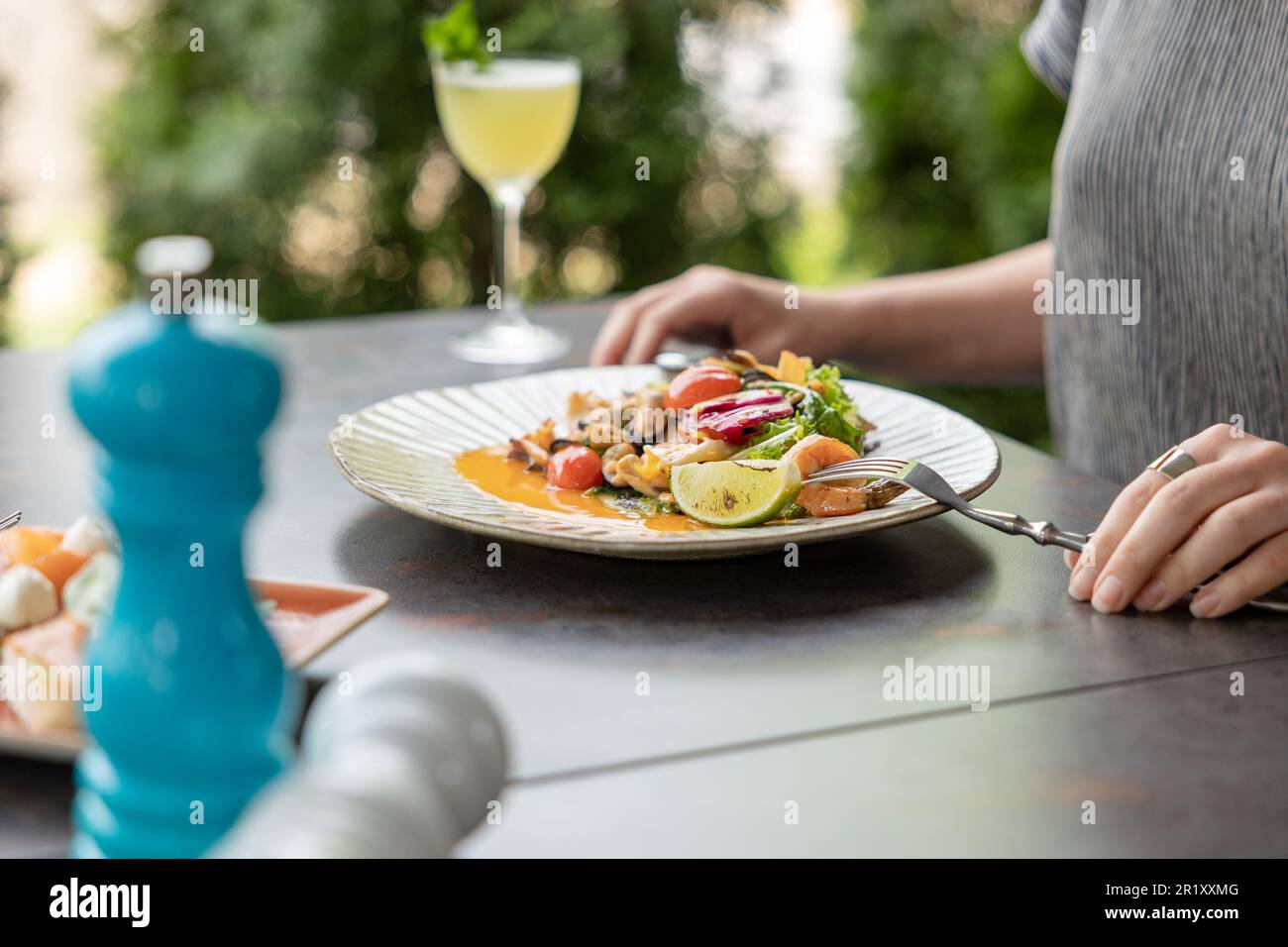 Les mains des femmes mangent de la salade de fruits de mer, les mains sont seulement visibles, table servie par le restaurant. Repas d'été et cocktail Banque D'Images