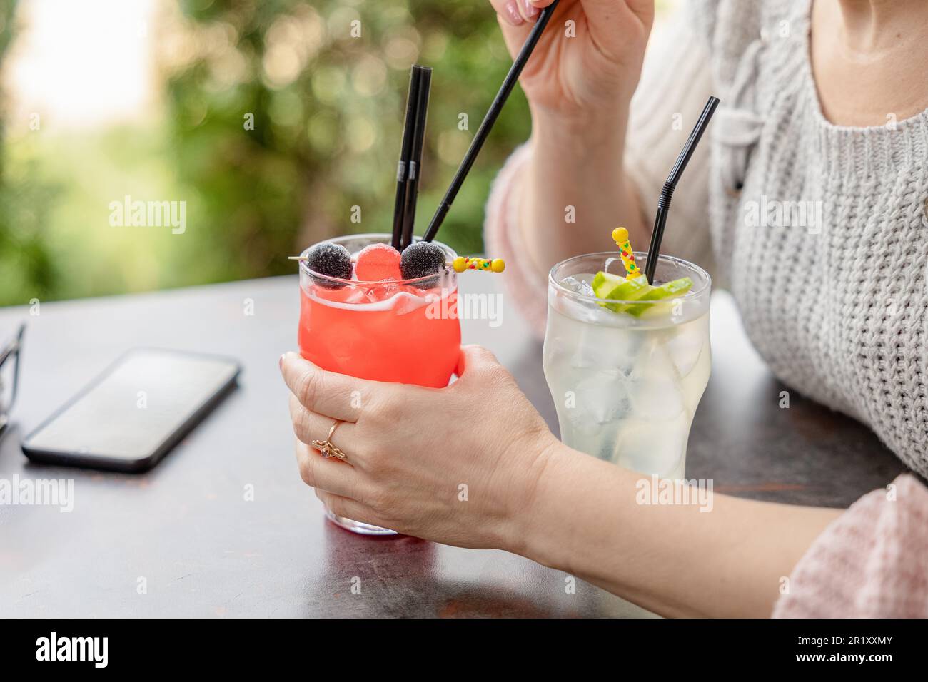 main féminine et deux verres à queue de cochon d'été dans le restaurant en plein air. femme essayant des cocktails Banque D'Images