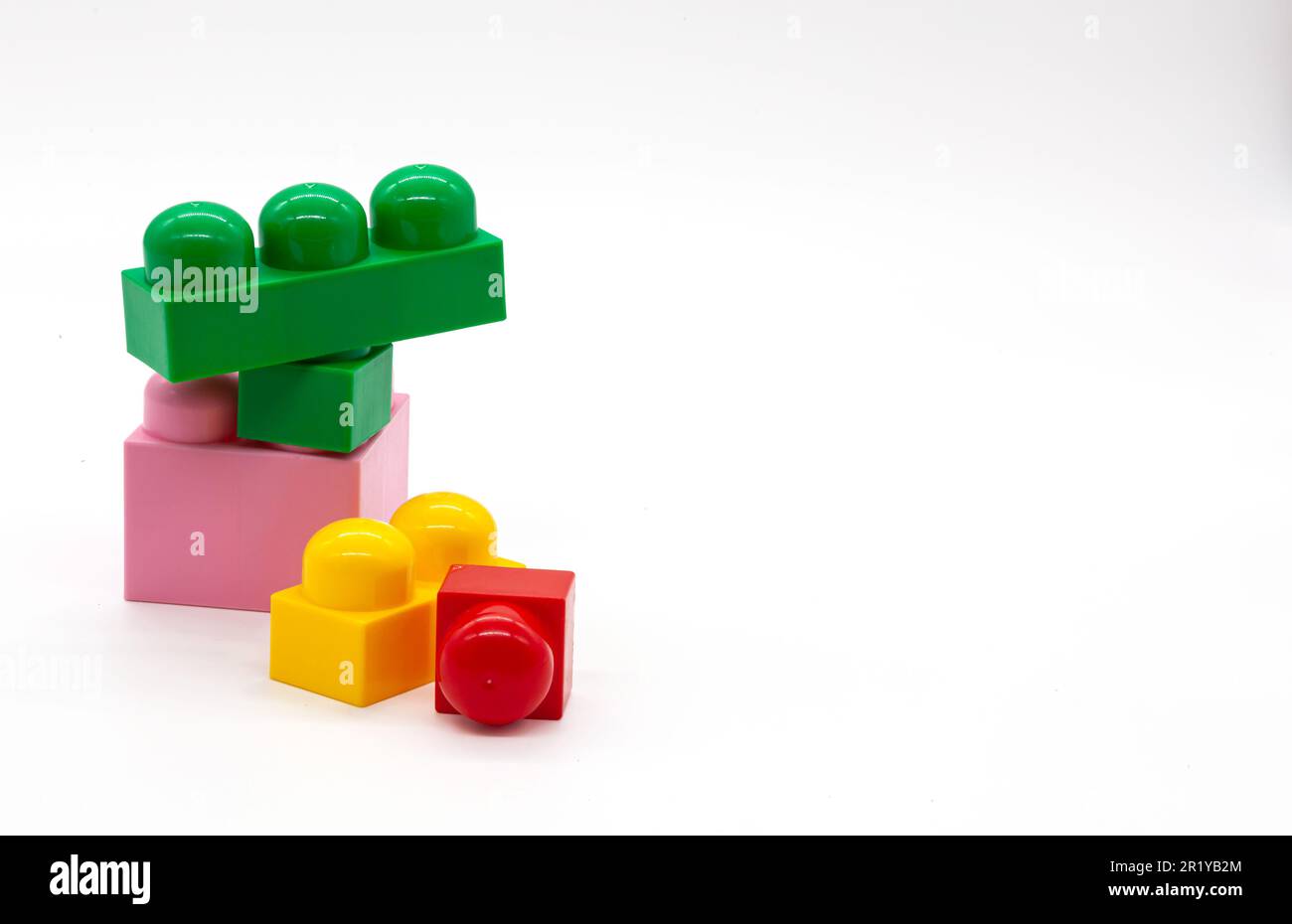 Constructeur de jouets pour enfants lego différentes tailles. Blocs rouge, rose et jaune et vert. Photo de haute qualité. Isolé. Banque D'Images