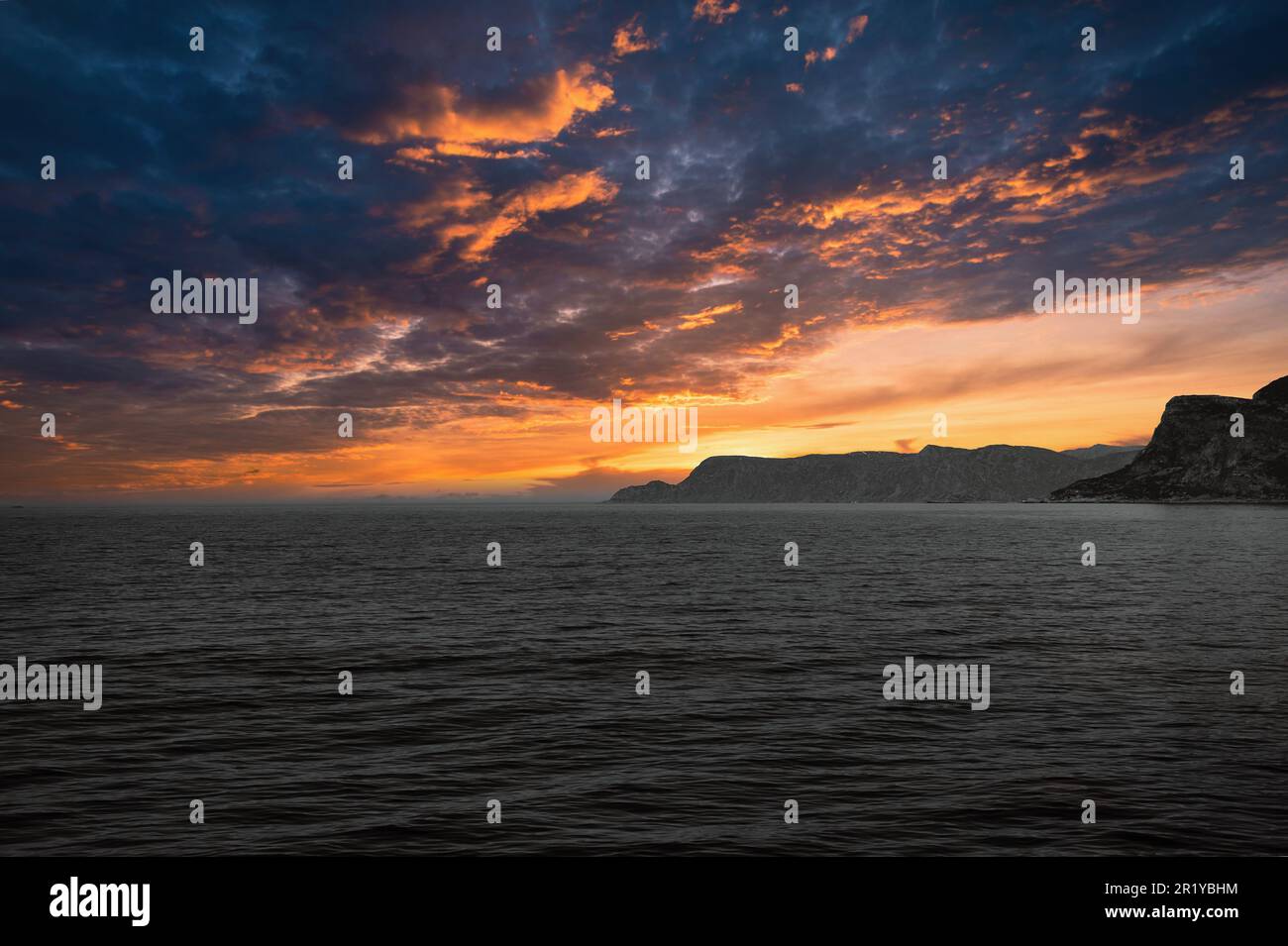 Vue de la mer à l'ouest du Cap en Norvège au coucher du soleil avec des rayons du soleil et de lourds nuages. Vagues au premier plan, rochers en arrière-plan. Le plus à l'ouest Banque D'Images