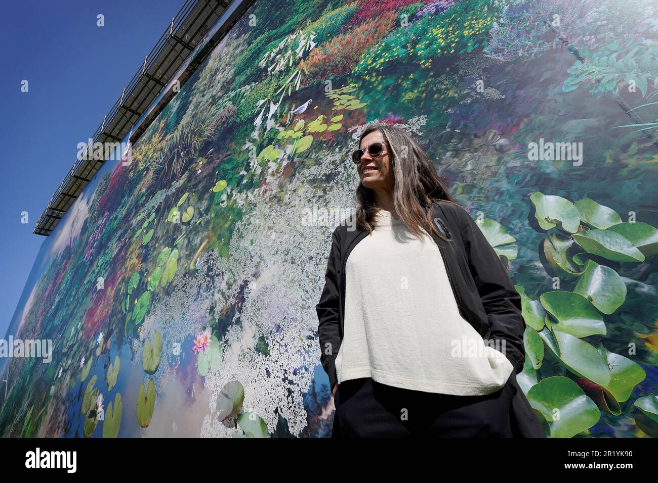 L'artiste Catherine Nelson pose avec son installation Planet Wakehurst, au Wakehurst Royal Botanic Gardens Kew, à Ardingly, West Sussex. La toile de 1 550 mètres carrés - l'équivalent de 25 bus à impériale et l'une des plus grandes installations extérieures du Royaume-Uni - présente un montage photo des collections de plantes les plus prestigieuses de Wakehurst Gardens et est enveloppée autour de la maison de caractère élisabéthaine classée au premier rang. Les visiteurs peuvent voir l'exposition depuis une plate-forme de 33ft haut offrant des vues sur le paysage sauvage de Wakehurst et les South Downs. Date de la photo: Mardi 16 mai 2023. Banque D'Images
