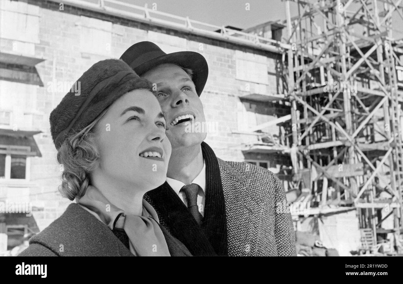 Dans le 1950s. Un jeune couple photographié sur un chantier où de nouveaux immeubles d'appartements sont en cours de construction. Ils regardent vers le haut, peut-être à leur propre appartement bientôt prêt à entrer. Suède 1957. Banque D'Images
