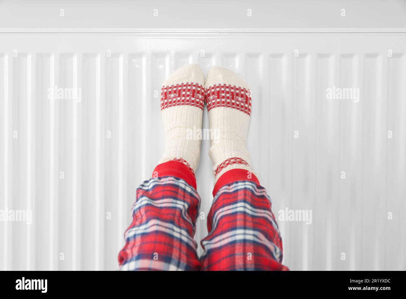 Petite fille réchauffant les pieds près du radiateur de chauffage à l'intérieur, gros plan Banque D'Images