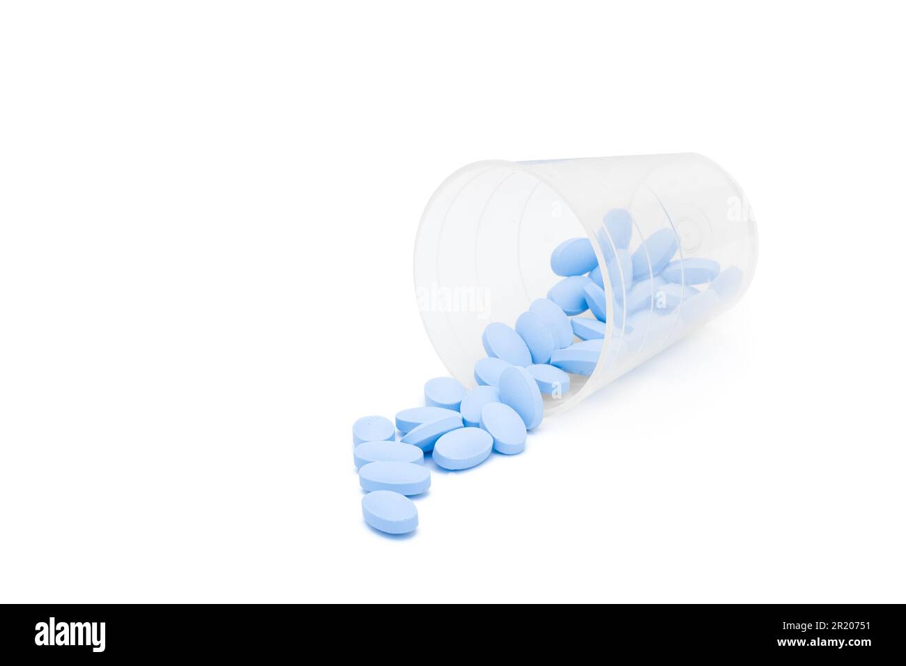Des pilules bleues ont été déversées hors de la tasse à médicaments Banque D'Images