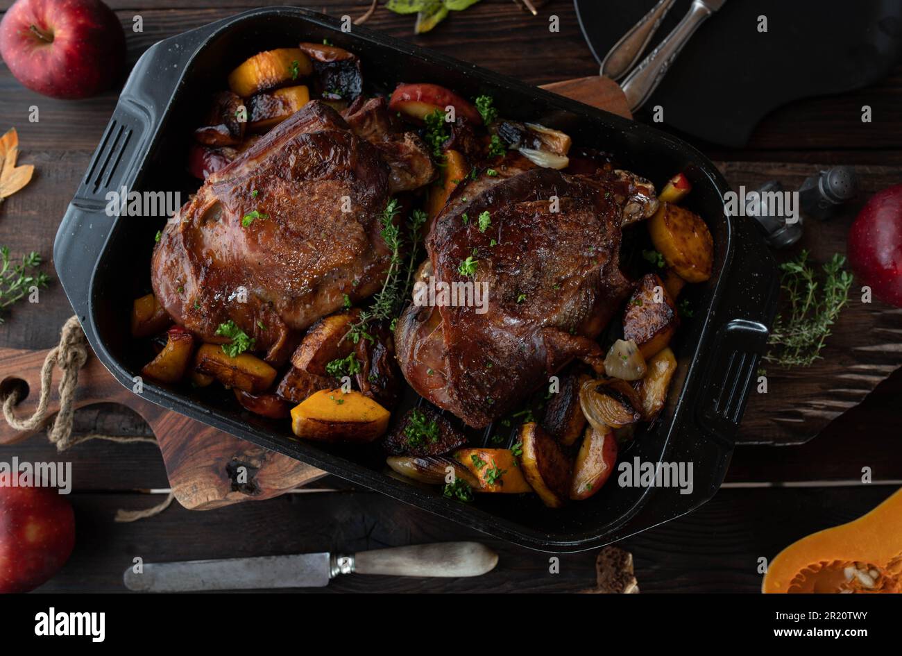 Plat à viande pour Thanksgiving avec queues de dinde rôties. Servi avec de la pumkine au noyer cendré, des pommes rouges, des oignons dans une rôtissoire sur une table rustique en bois Banque D'Images