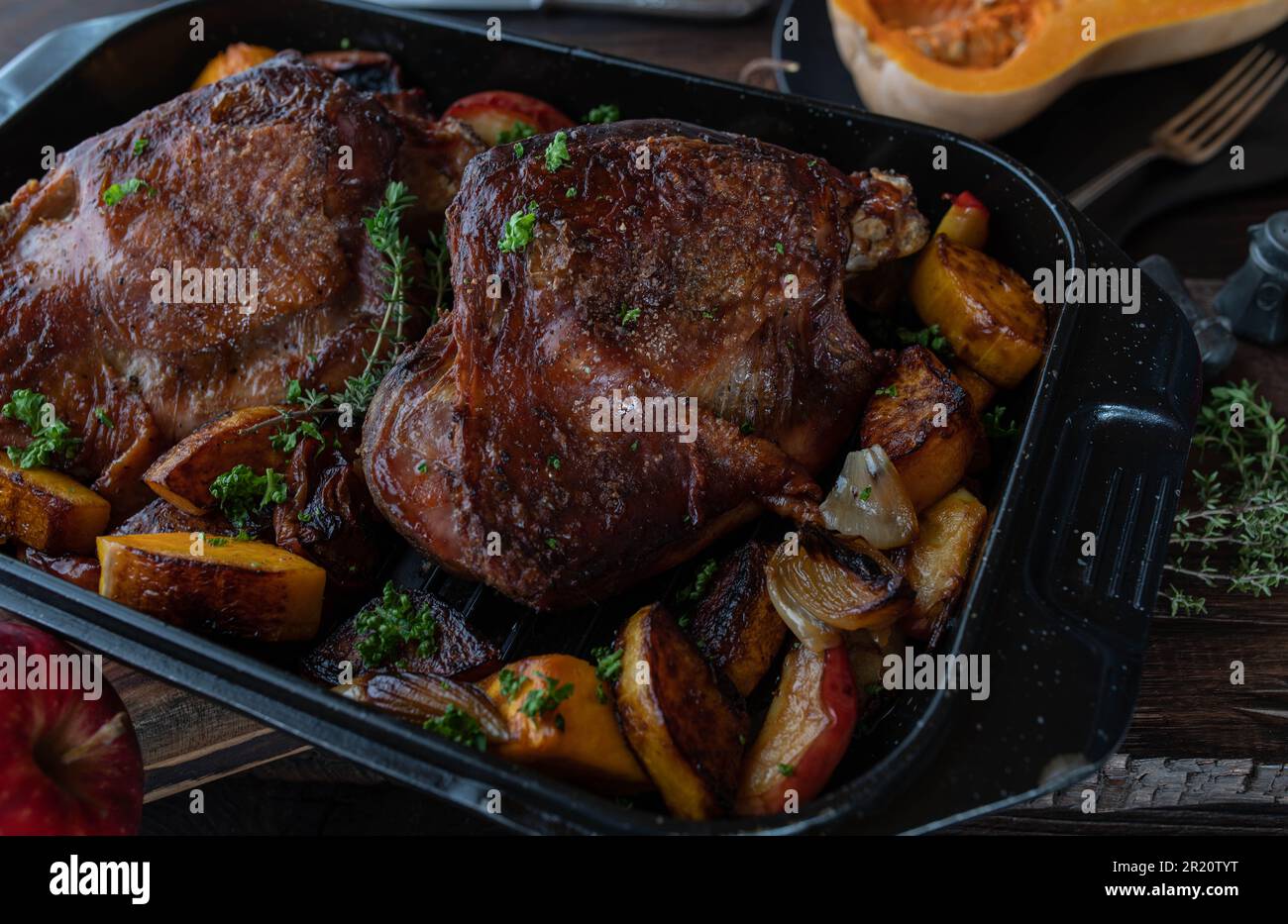 Plat à viande pour Thanksgiving avec queues de dinde rôties. Servi avec de la pumkine au noyer cendré, des pommes rouges, des oignons dans une rôtissoire sur une table rustique en bois Banque D'Images