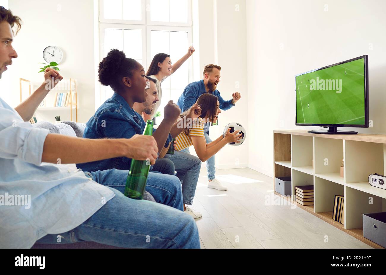 Joyeux et joyeux, divers amis crient tout en regardant un match de football à la télévision à la maison Banque D'Images