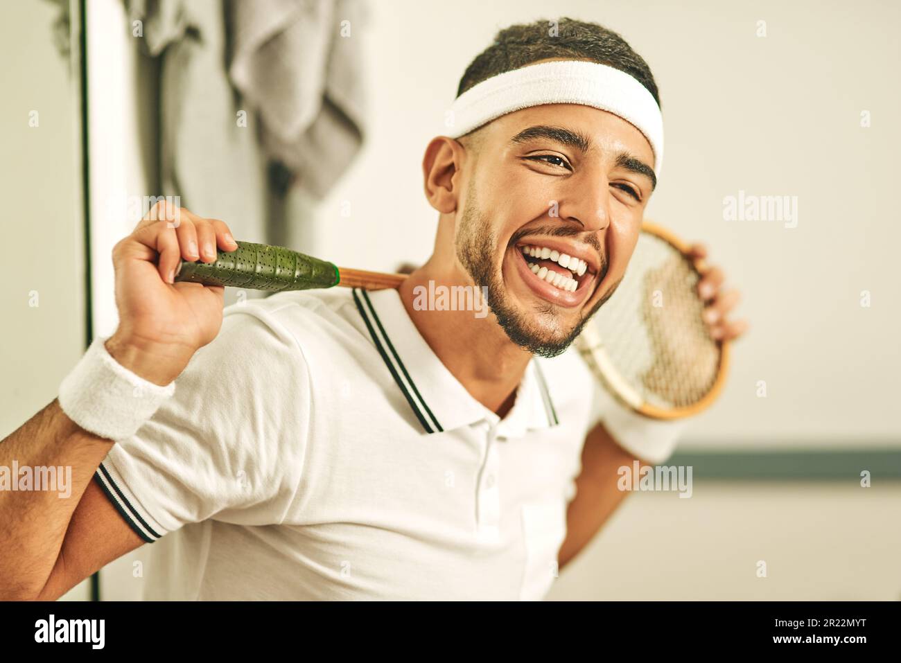 C'est un rire une minute dans ce club de squash. Portrait d'un jeune homme  heureux tenant sa raquette de courge dans le vestiaire Photo Stock - Alamy