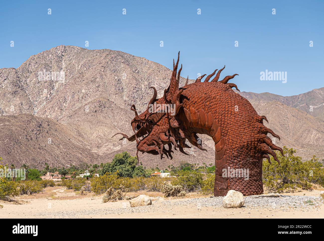 Borrego Springs, CA, Etats-Unis - 24 avril 2023 : statue de dinosaure géant préhistorique en métal rouillé brun, tête de dos, sur un désert sablonneux sous ciel bleu, Banque D'Images
