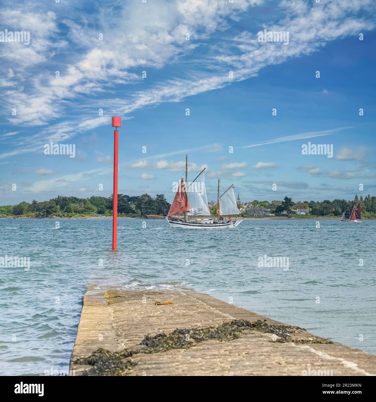 Un vieux voilier sur l'île d'Ile-aux-Moines, un magnifique paysage marin dans le golfe du Morbihan, en Bretagne, avec l'église de l'île d'Arz en arrière-plan Banque D'Images