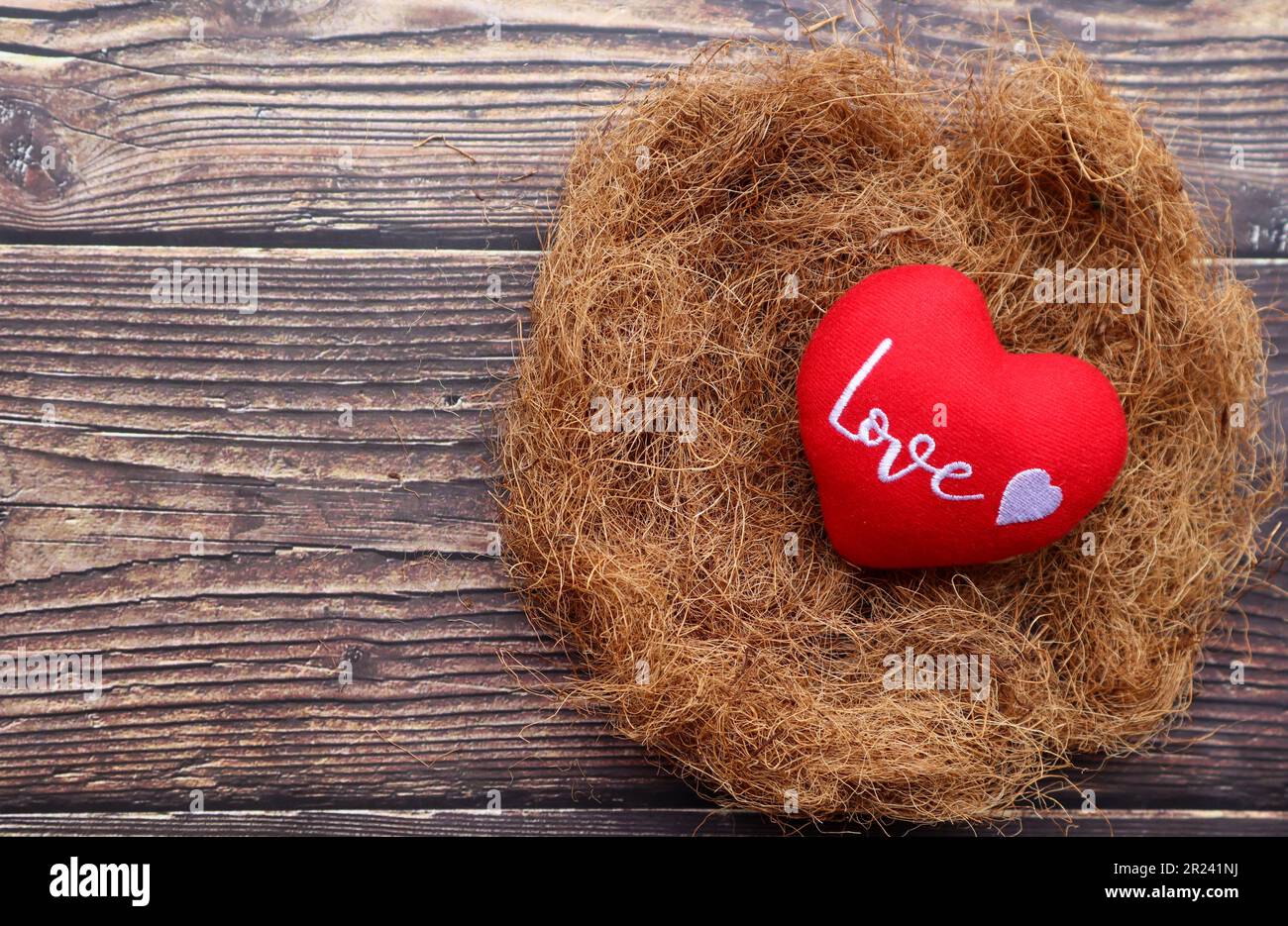 Nid d'amour - coeur rouge avec lettre amour dans nid d'oiseau sur fond de bois avec espace de copie: Amour, romance et concept de la Saint-Valentin Banque D'Images