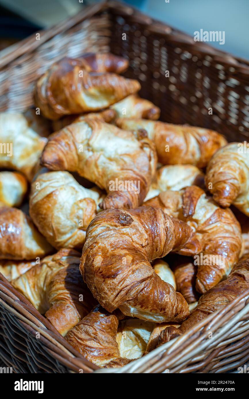 Un gros plan d'un panier en osier de croissants fraîchement cuits. Banque D'Images